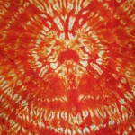 Another view of the detailed circular dye patterns on this orange silk shibori scarf by Maureen Jakubson